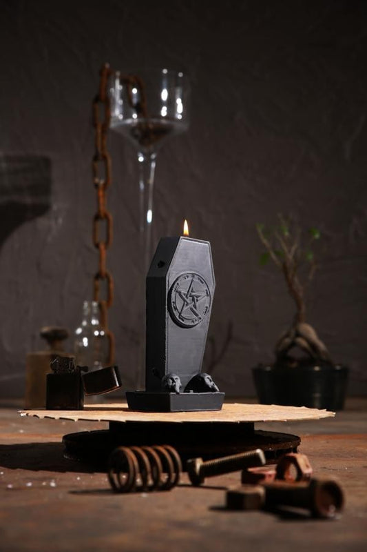 Schwarze, sargförmige Kerze mit Pentagram-Aufdruck und zwei kleinen Totenkopfen am Fuß
