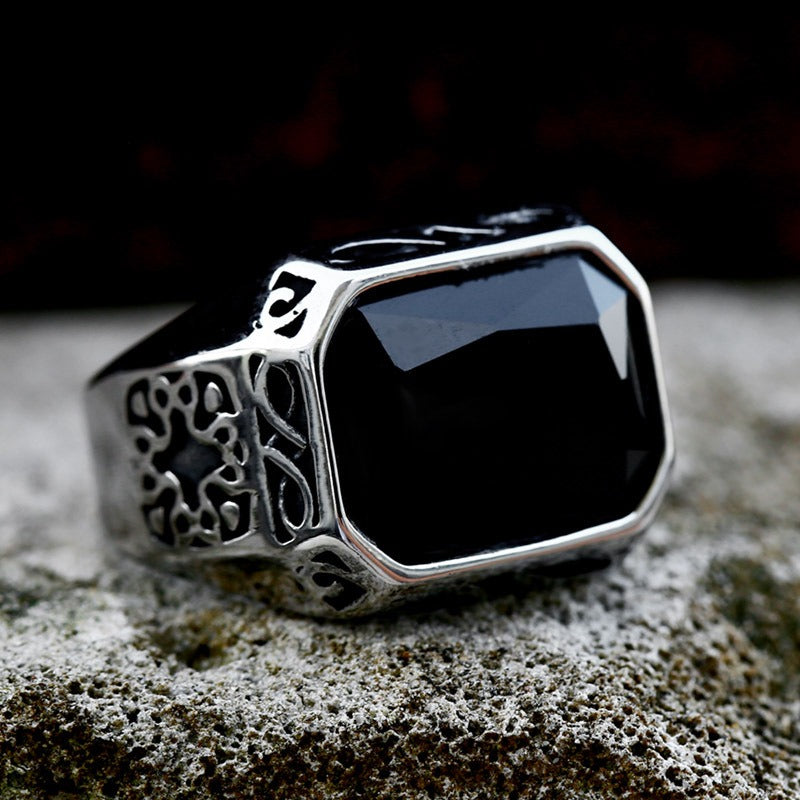 Breiter, silberfarbender Edelstahlring mit schwarzem, rechteckigem Stein und an den Seiten vielen kleinen eingravierten Mustern