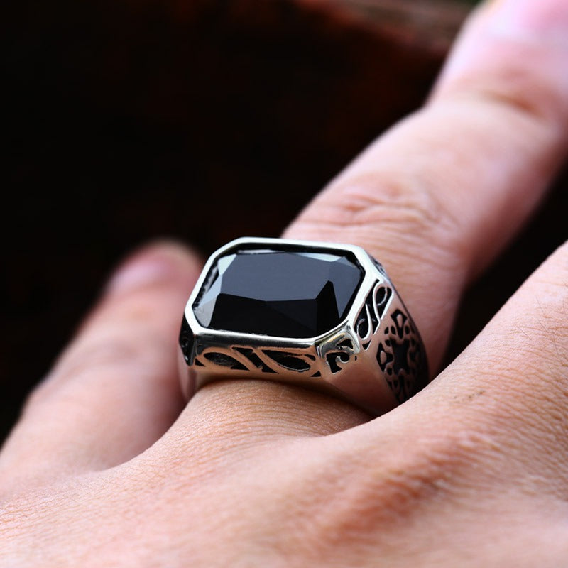 Breiter, silberfarbender Edelstahlring mit schwarzem, rechteckigem Stein und an den Seiten vielen kleinen eingravierten Mustern