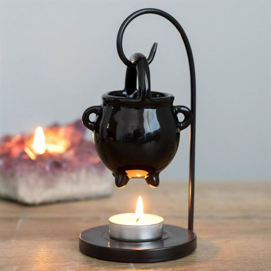Duftlampe in Form eines Hexenkessels, die an einem gebogenen Draht über einem Teelichthalter hängt
