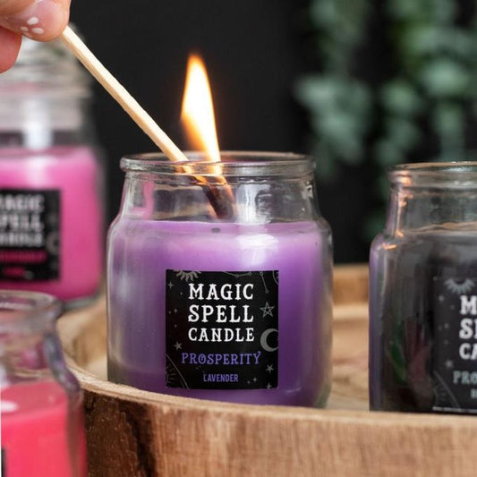 Glas mit lilafarbender Kerze mit Aufkleber mit der Aufschrift 'Magic Spell Candle Prosperity'