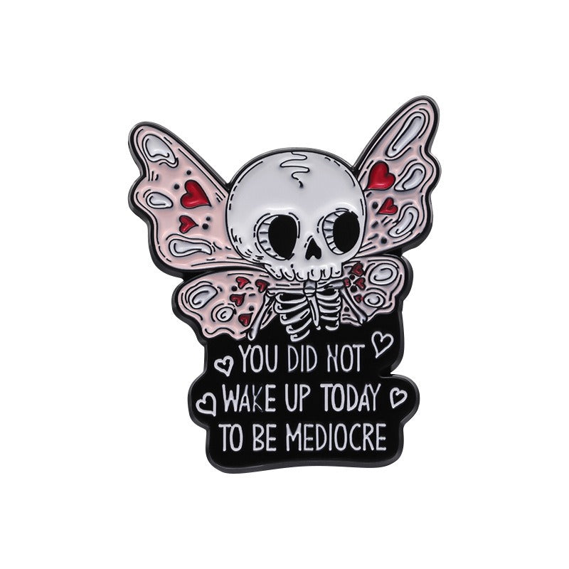 Kleiner Emaille-Anstecker MEDIOCRE ENAMEL PIN mit Skelett mit Flügeln und Aufschrift 'You Did Not Wake Up Today To Be Mediocre' von Moon Attic