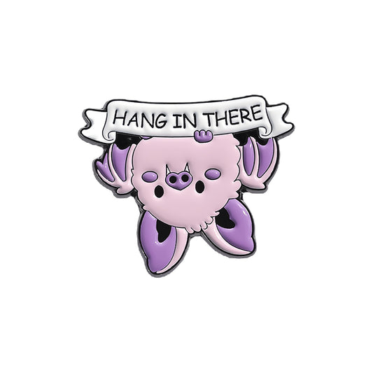 Rosafarbender Emaille-Anstecker HANG IN THERE ENAMEL PIN in Form einer niedlichen Fledermaus mit der Aufschrift 'Hang In There' von Moon Attic